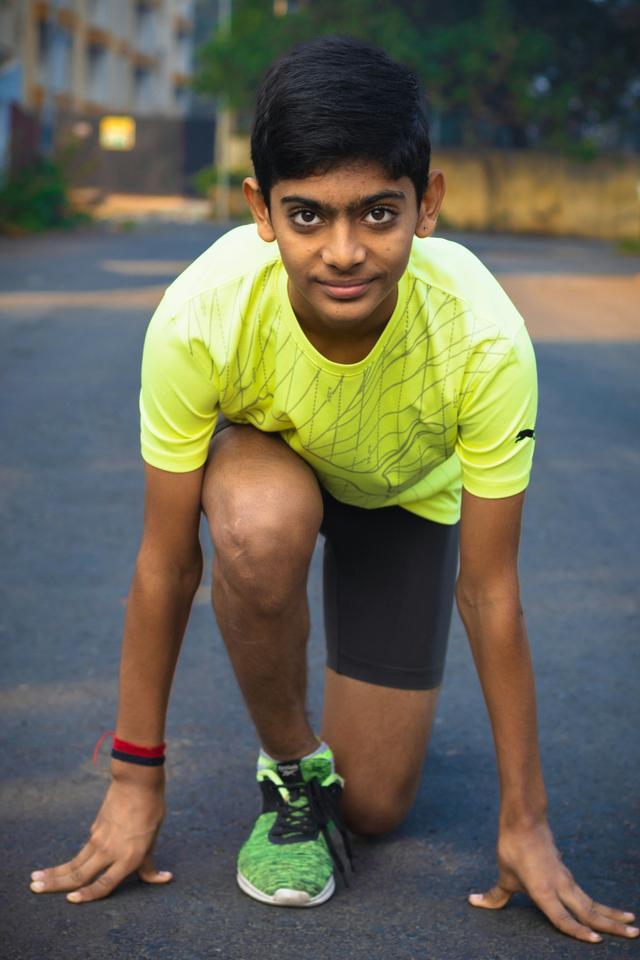 Boy in the running start position wearing the Nike Neon Impact Performance Tee