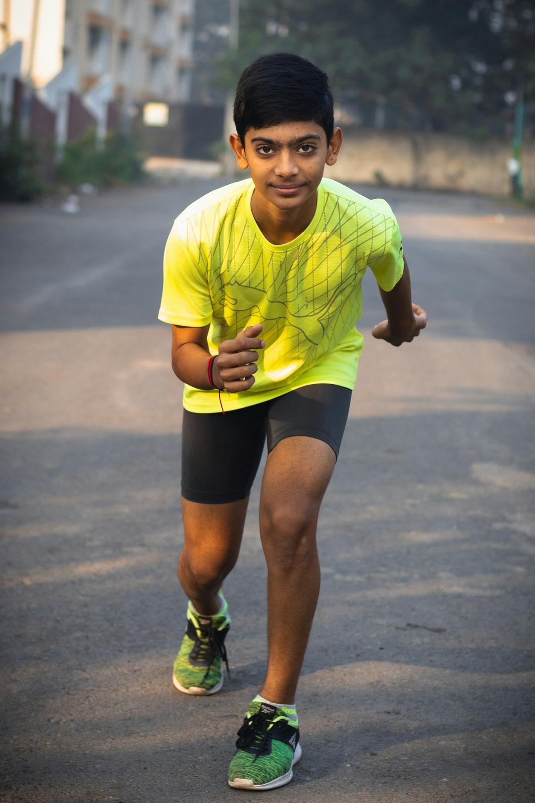 Boy in the running position wearing a Nike Neon Impact Performance Tee